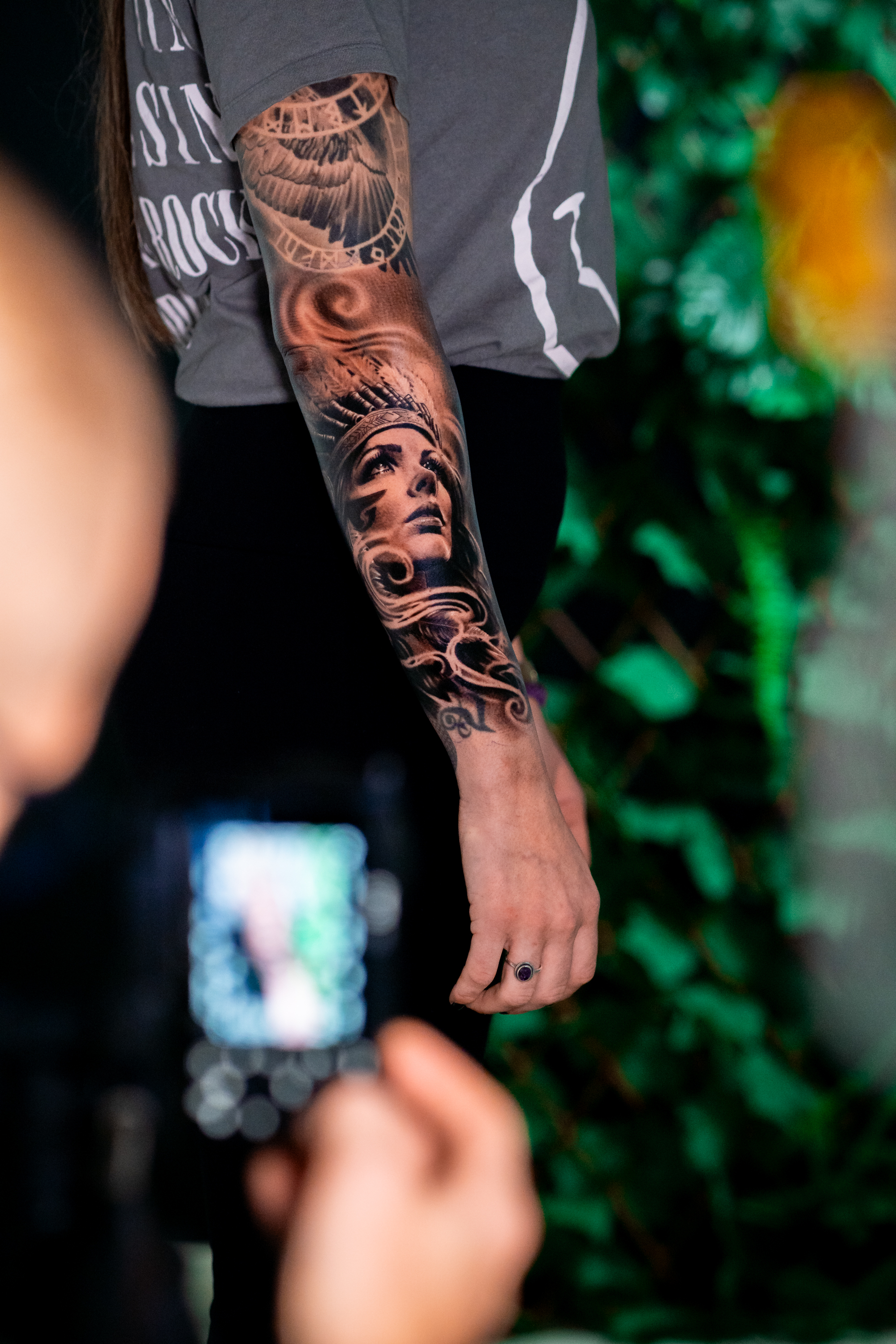 Detalle de tatuaje retrato de mujer con tocado de plumas en el antebrazo