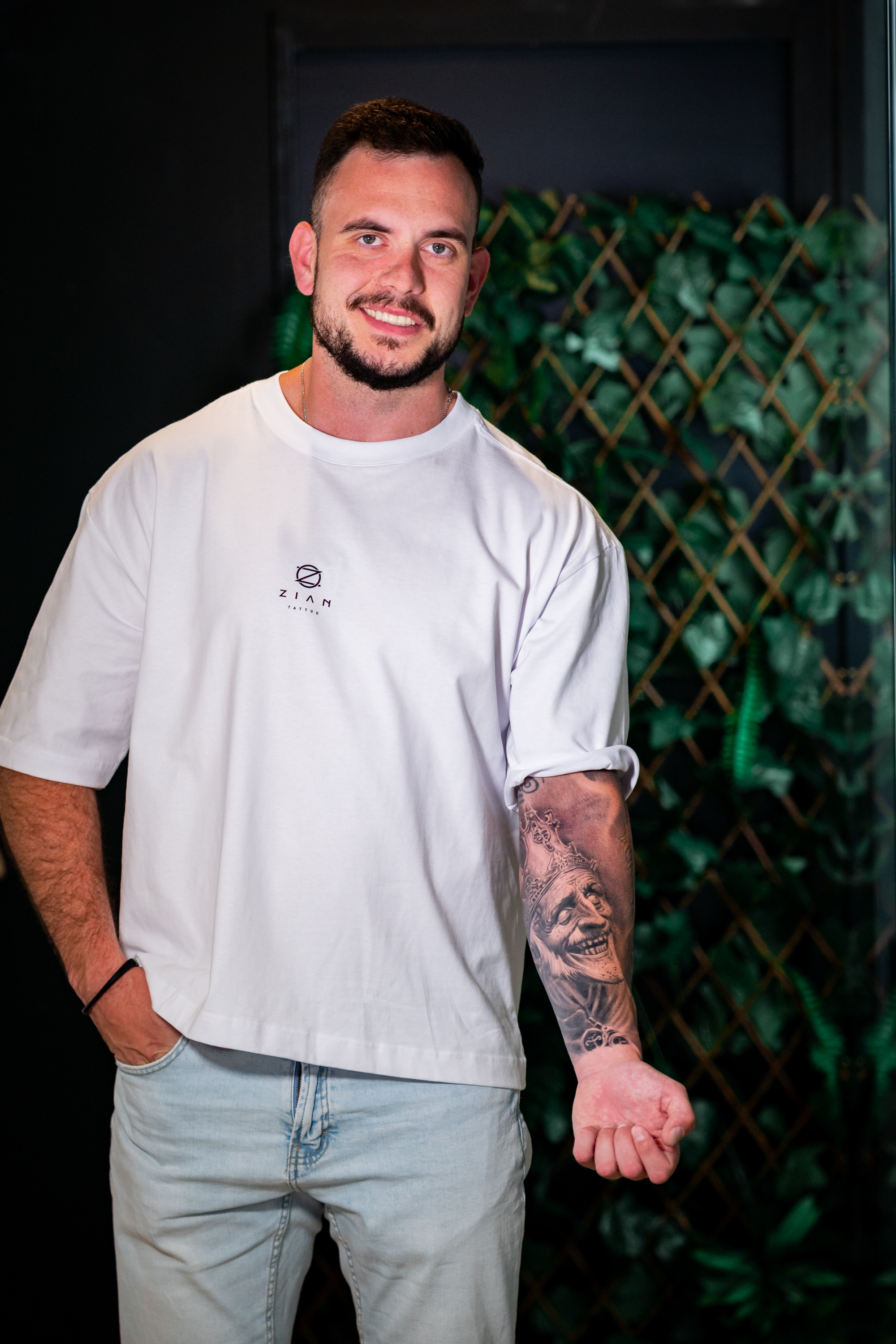 Tatuaje retrato de rey con corona riendo en el antebrazo